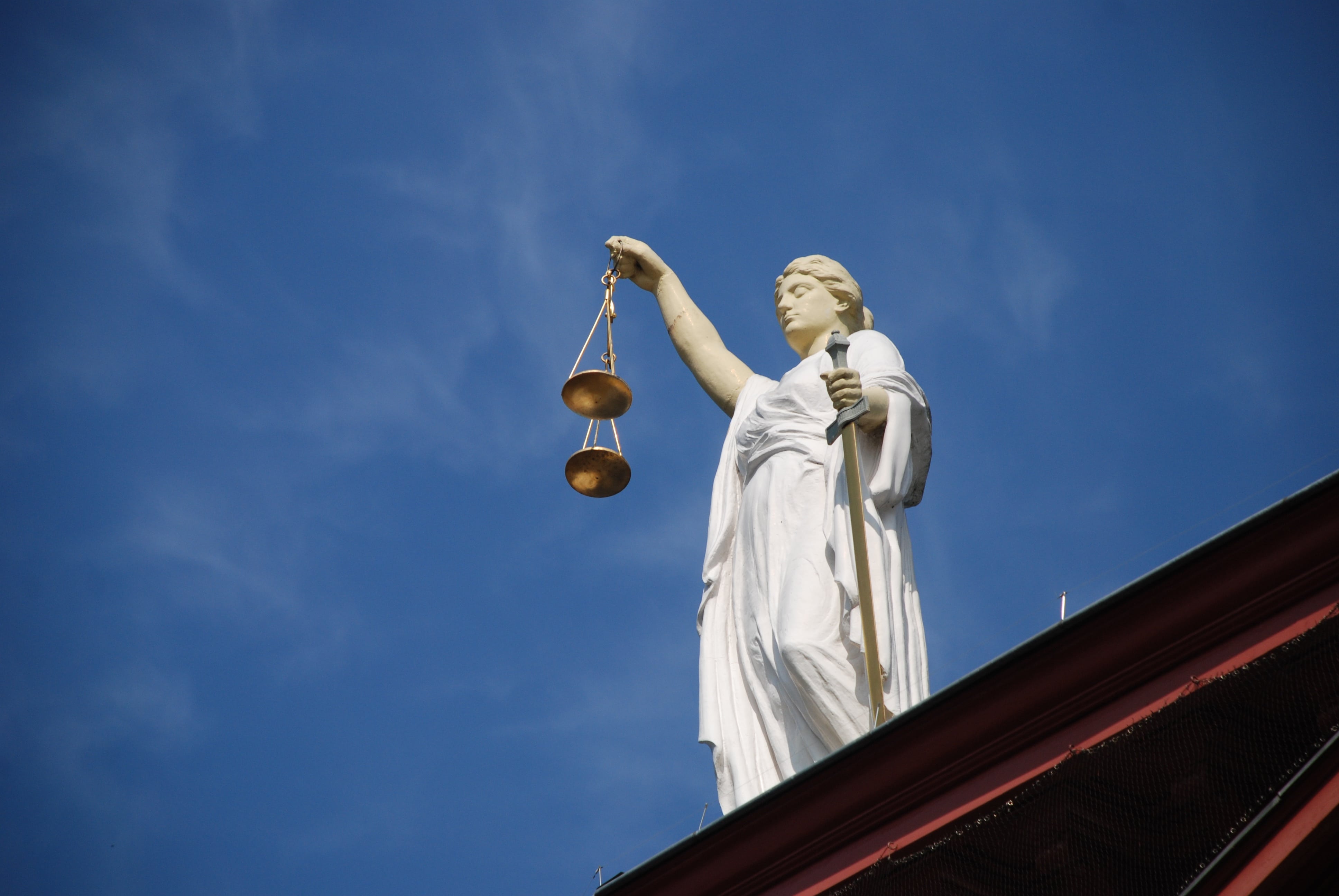 Bagaimana kontrak pintar Ricardian akan mempengaruhi kita. Gambar: Patung Keadilan, memegang sisiknya di hadapan langit yang hebat.